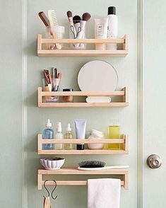 three wooden shelving shelves holding various bathroom products and personal care items in front of a green door