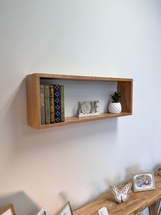 two bookshelves on the wall above a wooden table with pictures and vases