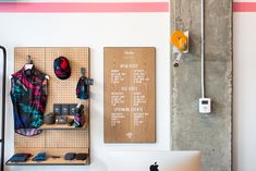 there is a computer on the desk in front of some wall hangings with hats and other items