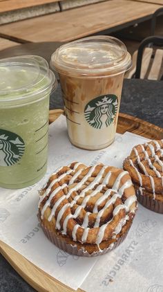 two pastries sitting on top of a wooden tray next to a cup of coffee