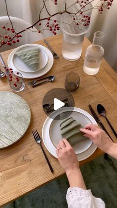 the woman is setting the table with her placemats and napkins on it