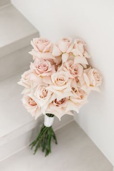 a bouquet of pink roses sitting on top of a white wall next to some stairs