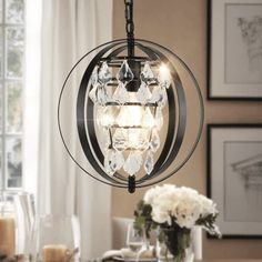 a chandelier hanging over a dining room table with flowers in the vases