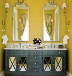 a bathroom with yellow walls and two mirrors