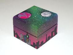 a small box with two stickers on it sitting on a white surface next to a cityscape