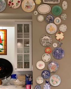 a kitchen with plates on the wall and stained glass in the cabinet door window behind it