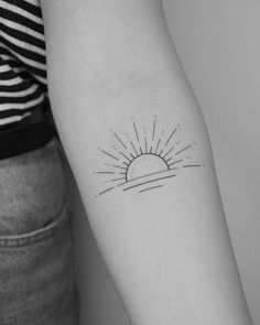 a woman's arm with a small sun tattoo on the left side of her arm