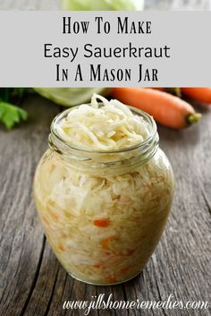 a mason jar filled with sauerkraut on top of a wooden table next to carrots and celery