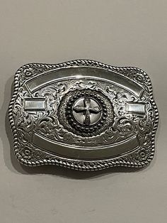 a silver belt buckle with a cross on it