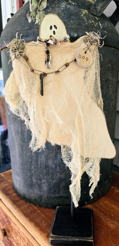 a halloween decoration with a ghost hanging from it's back on top of a wooden table