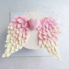 a cake with pink and white icing on it's wings, decorated with a heart