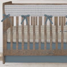 a baby crib with blue bows on the top and bottom rail, in front of a white wall