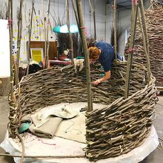 a woman working on a sculpture made out of branches