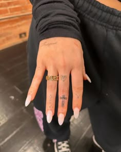 a woman's hand with tattoos on it and a cross tattoo on the middle finger