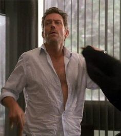 a man in white shirt standing next to a black cat