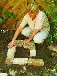 a woman kneeling down next to bricks in the ground