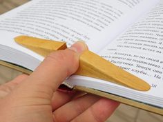 a person is holding a book with a wooden object in it's hand and reading the book