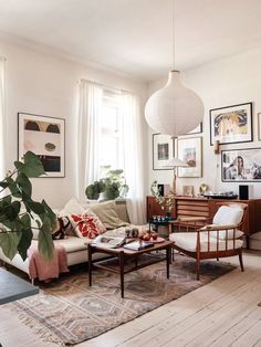 a living room filled with lots of furniture and pictures on the wall above it's windows