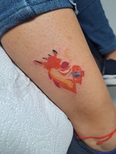 a woman's leg with an orange and red tattoo on her left side thigh