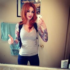 a woman taking a selfie in the mirror with her cell phone and tattoos on