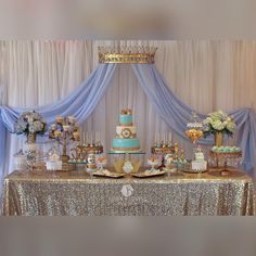 a table topped with lots of cakes and desserts next to a curtained wall