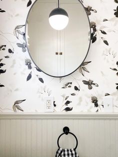 a bathroom with a round mirror on the wall next to a black and white checkered towel