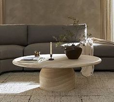 a living room with a couch, coffee table and vases on the floor in front of a window