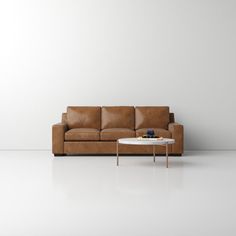 a brown leather couch sitting next to a white table on top of a white floor