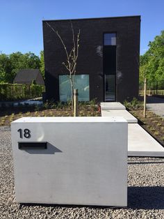 a white box sitting in front of a building with a tree growing out of it