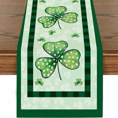 a green and white table runner with shamrocks on the front, along with four leaf clover