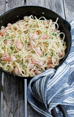 pasta with shrimp and parsley in a cast iron skillet on a wooden table