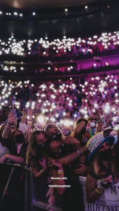 a group of people standing in front of a crowd at a concert with their hands up