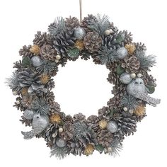 a wreath with pine cones and ornaments hanging from a hook on a white background,