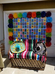 a colorful chair sitting in front of a garage door with paper flowers on the wall