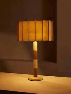 a lamp that is sitting on top of a wooden table next to a wall in a room