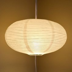 a white lamp hanging from the ceiling in a room with beige walls and flooring