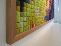 a colorful wall hanging on the side of a white wall next to a wooden frame