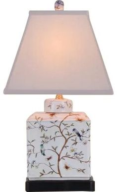 a lamp with a bird on it and a white shade over the light that is turned on