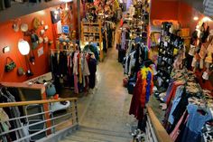 a store filled with lots of clothes and other items next to a stair case that leads up to the second floor