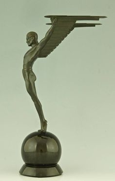 a bronze figurine holding a tray on top of a metal ball with wings