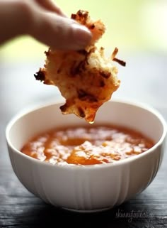 a person dipping something into a bowl of soup