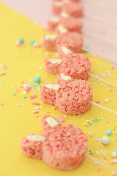 pink rice krispy treats are lined up on a yellow table