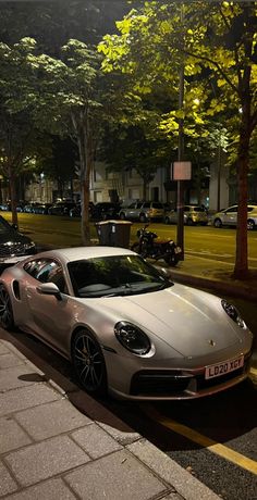 a silver sports car parked on the side of the road next to a tree lined street