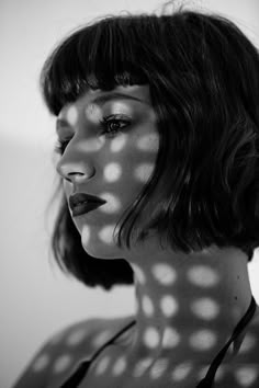 a black and white photo of a woman's face with shadows on the wall behind her