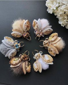 six pieces of broochies with feathers and pearls on them, sitting next to flowers