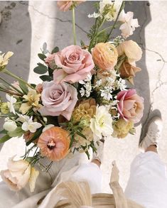 a bouquet of flowers sitting on top of a person's legs in the sun