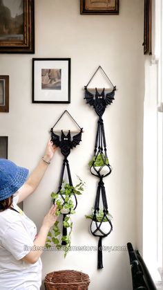 a woman is hanging plants on the wall