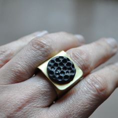 CAVITÀ band ring in brass with round slate carved with circular patterns. This type of processing gives it three-dimensionality thanks to the shades of chiaroscuro that are generated. It is an elegant and unique ring with a contemporary design, characterized by the contrast between gold and black. A small sculpture to wear! Each piece is unique and always different. Entirely handcrafted, handmade in Italy. The slate, which comes from the waste processing of companies in the province of Genoa, is Black Brass Rings For Gift, Black Stone Ring, Brass Band, Small Sculptures, Circular Pattern, Types Of Work, Genoa, Unique Ring, Chiaroscuro