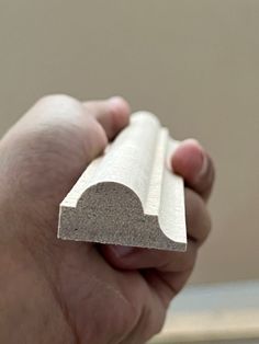 a hand holding a piece of concrete in it's left hand, with the end of an object visible