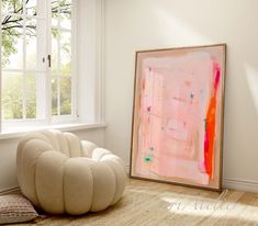 a painting sitting on top of a wooden floor next to a white chair and window